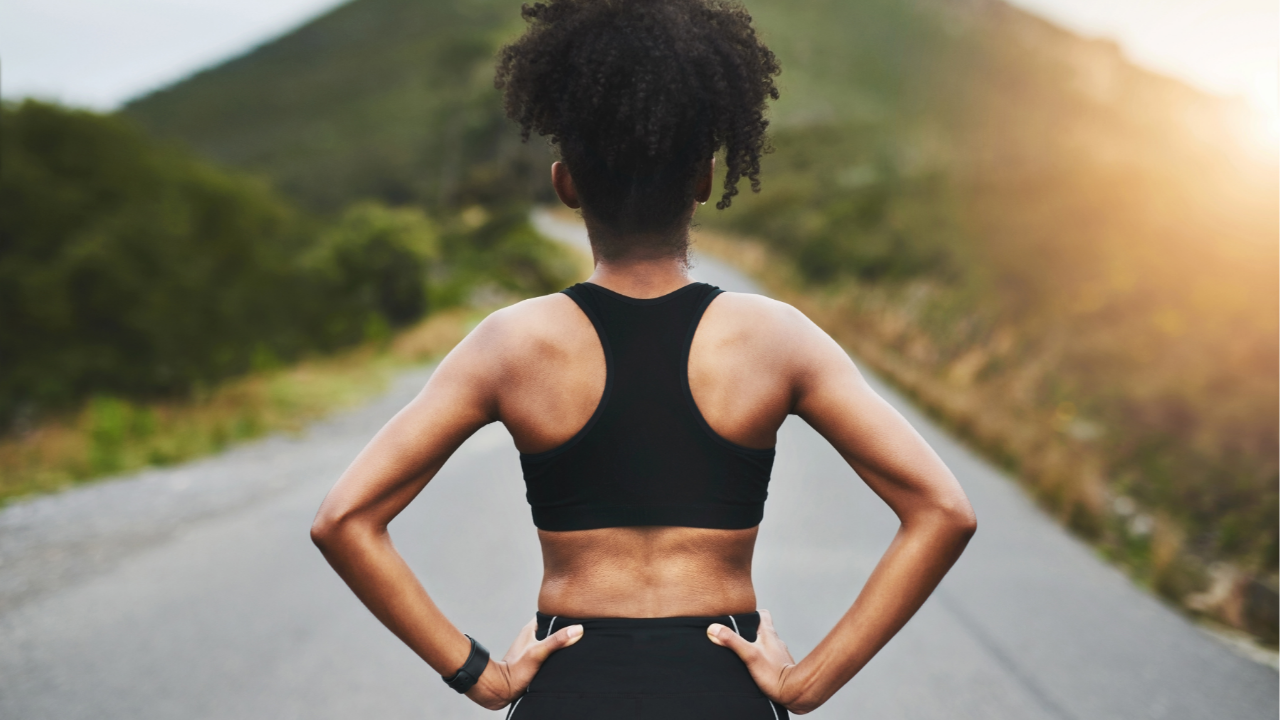 woman with hands on hips facing open road