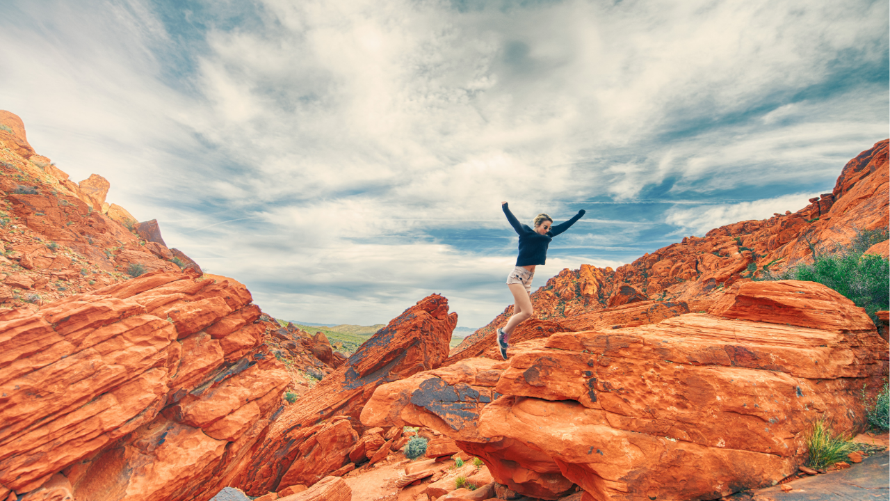 Women jumping on red rocks with arms wide open