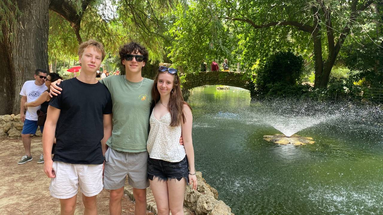 Three teenagers standing in front of a fountain in a park