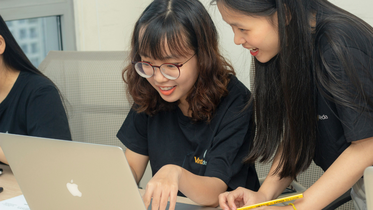 Two students looking at computer together and smiling