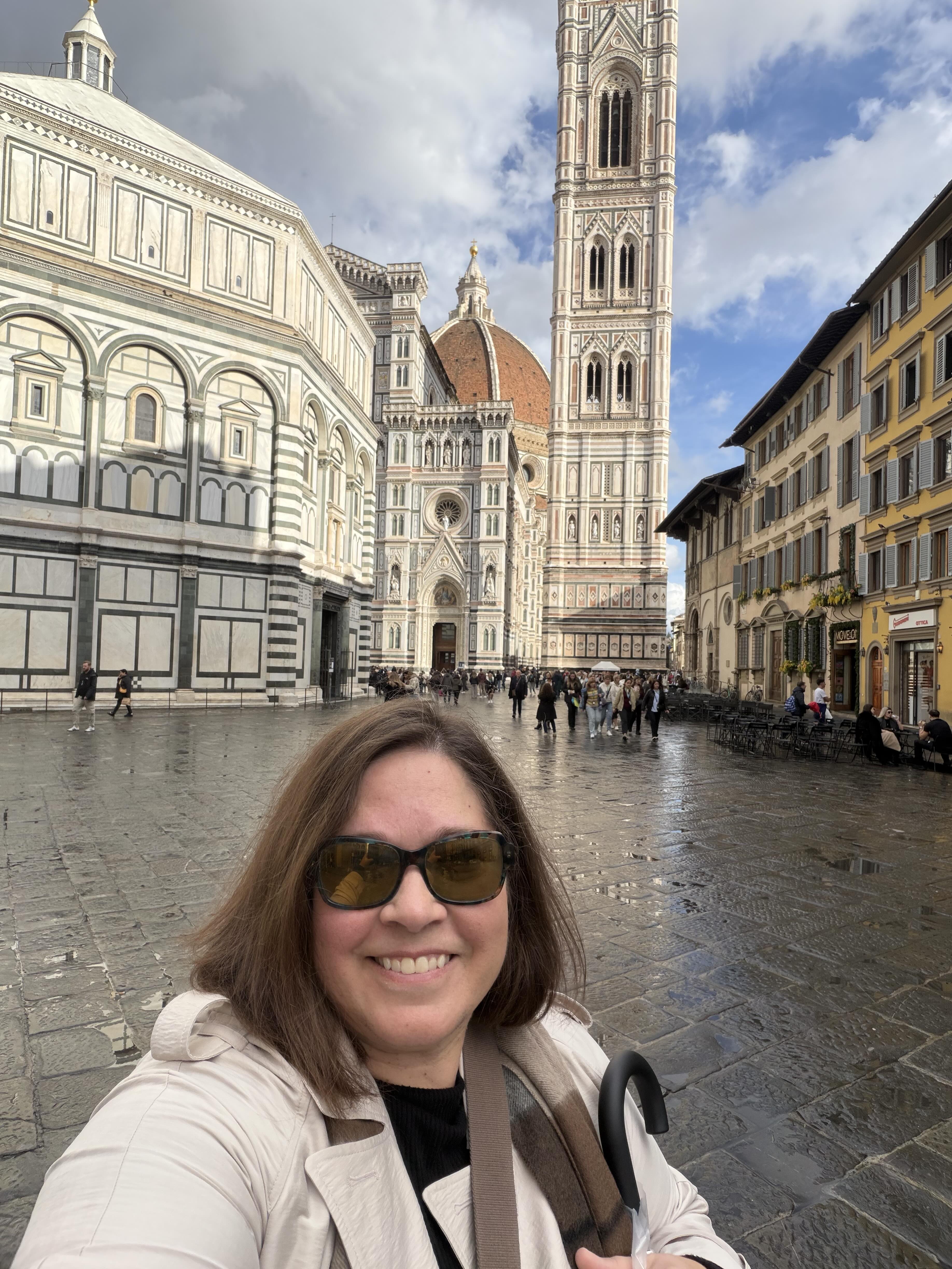 Tamsen Horton smiles in front of the Florence Duomo on a rainy day, symbolizing clarity and calm in business amidst complexity