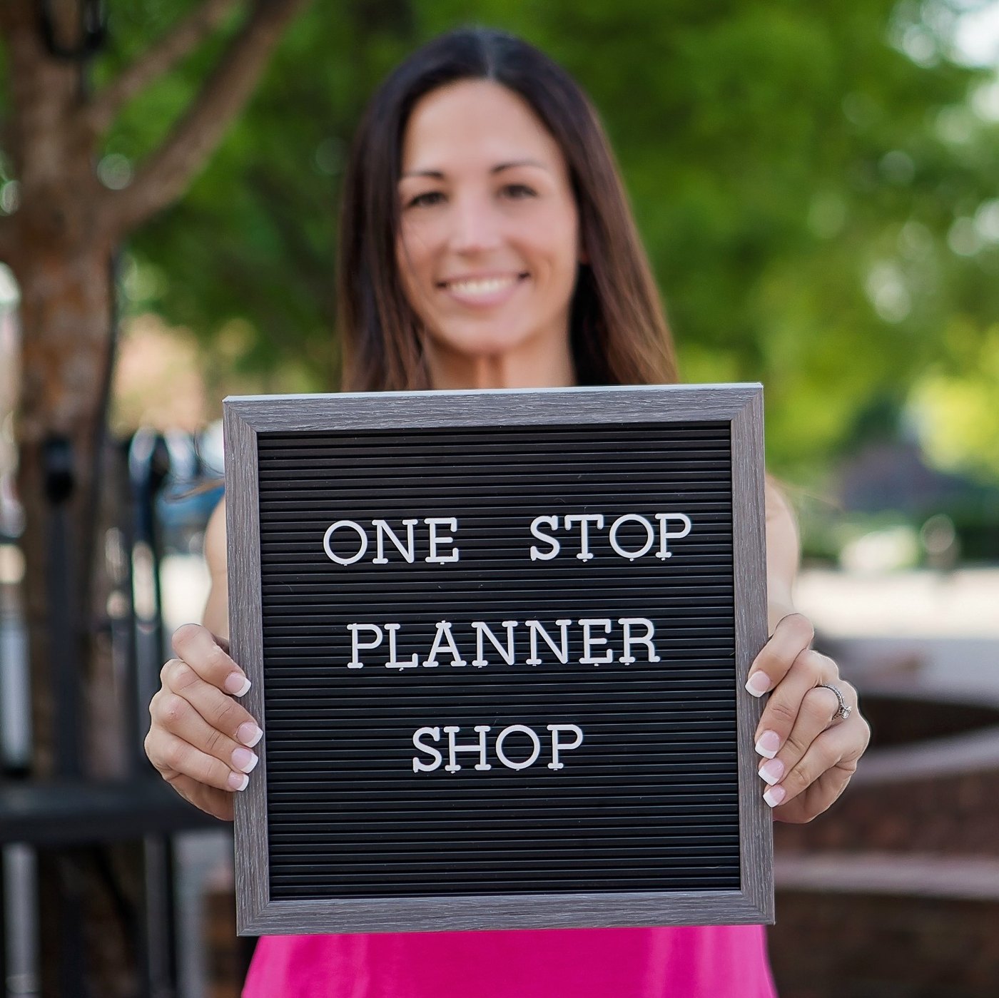 Kristin smiling behind a letter board that reads One Stop Planner Shop