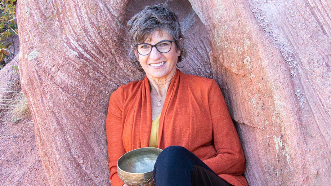 Female sound healer, playing the rim of a purple crystal singing bowls