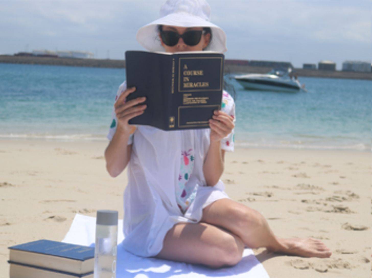 Tash reading A Course in Miracles on the beach