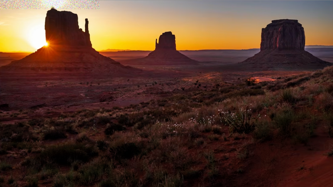 Monument Valley at sunrise with the horizon placed near the top of the frame, emphasizing the desert foreground