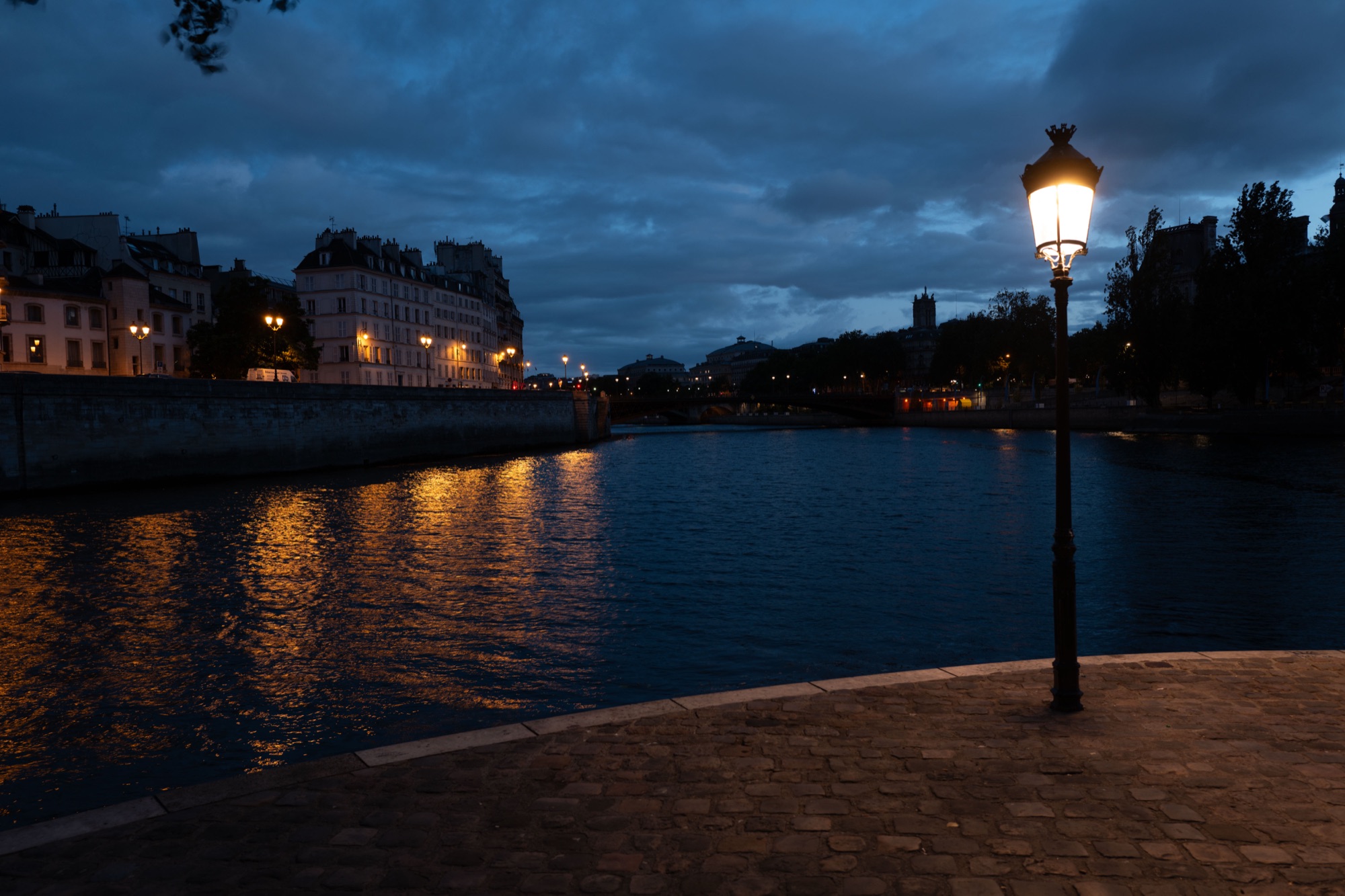 Before a Lightroom preset — flat RAW photo of a Paris riverside lamp at blue hour