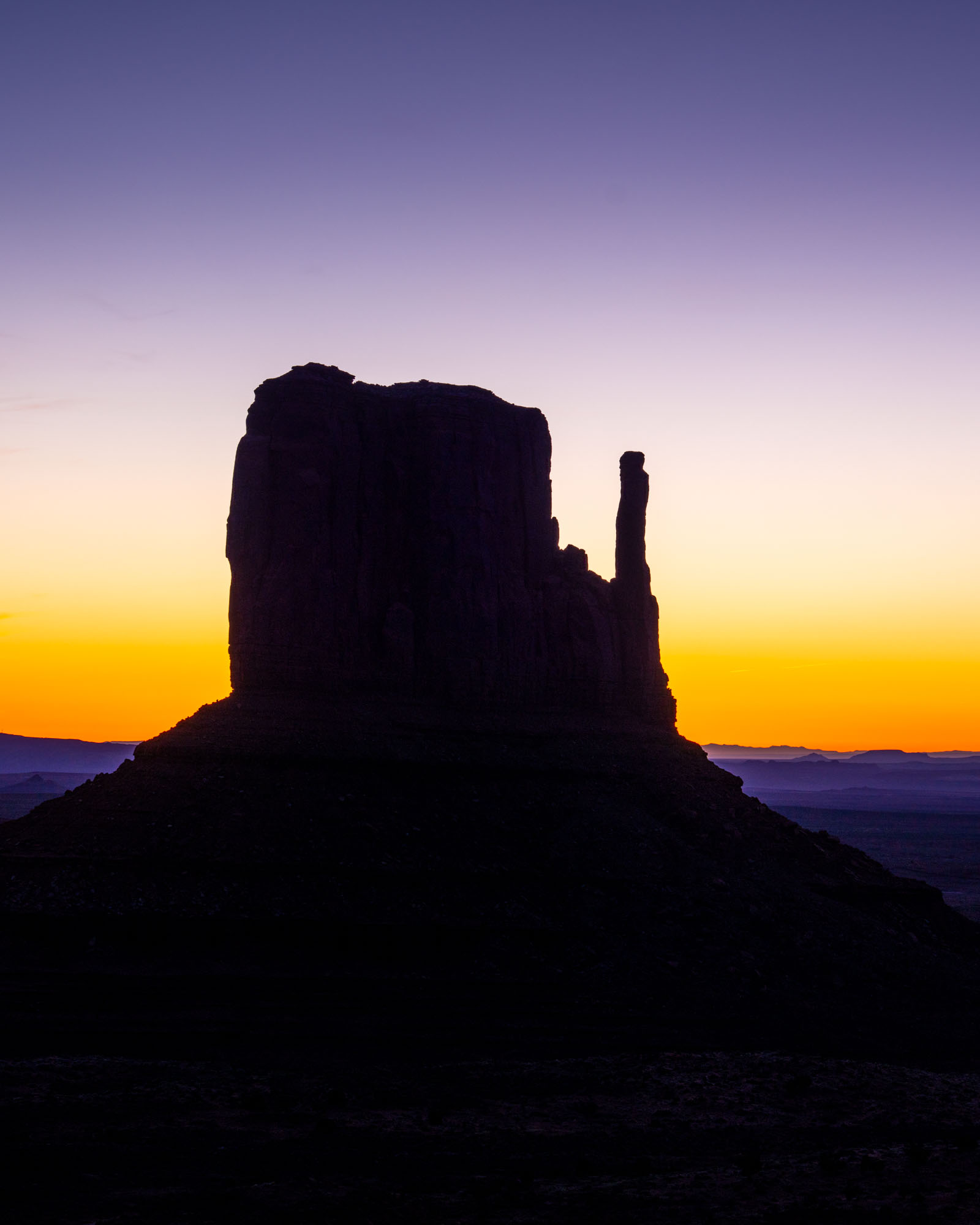 West Mitten Butte silhouetted against an orange and purple sunrise sky