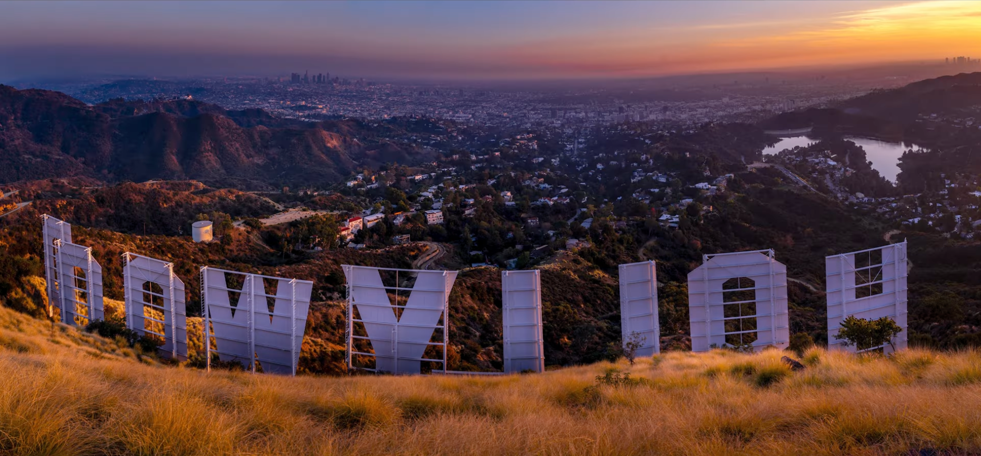 Standing behind the Hollywood Sign letters at sunset, looking down over Los Angeles, panorama
