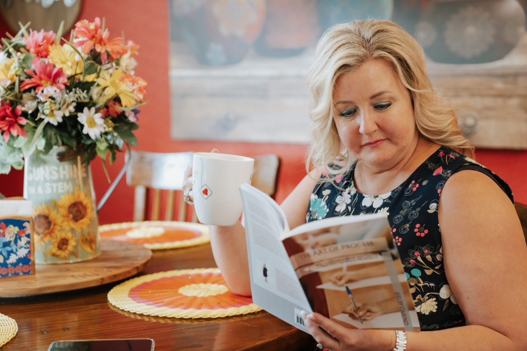 Shelby Carino reading a book with a cup of tea