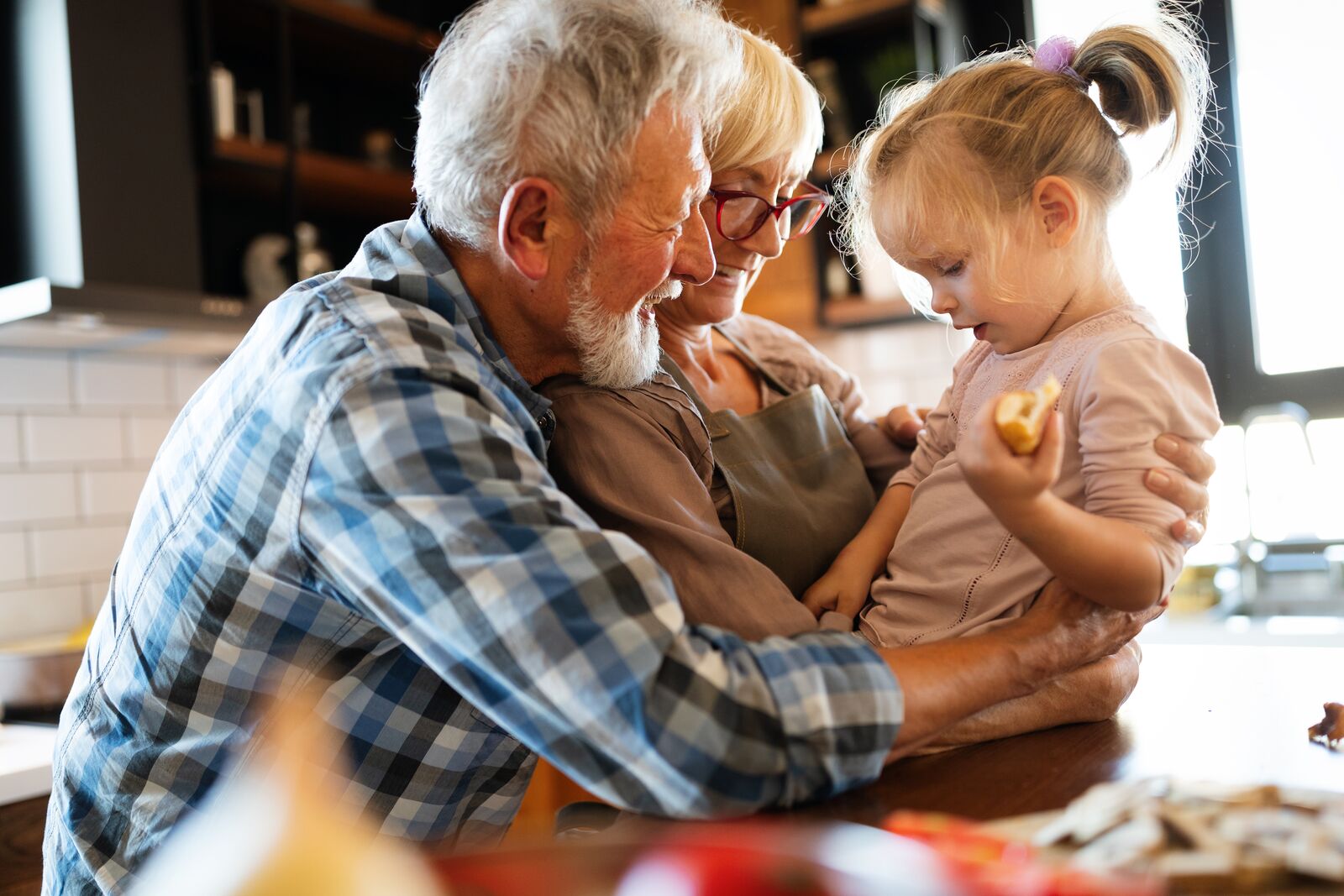 Grandparents playing with their grandchild in a kitchen – Super Visa for parents and grandparents in Canada