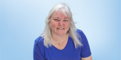RaNae Wright, ethics advisor for the Healing Touch Program, photographed against a light blue background.