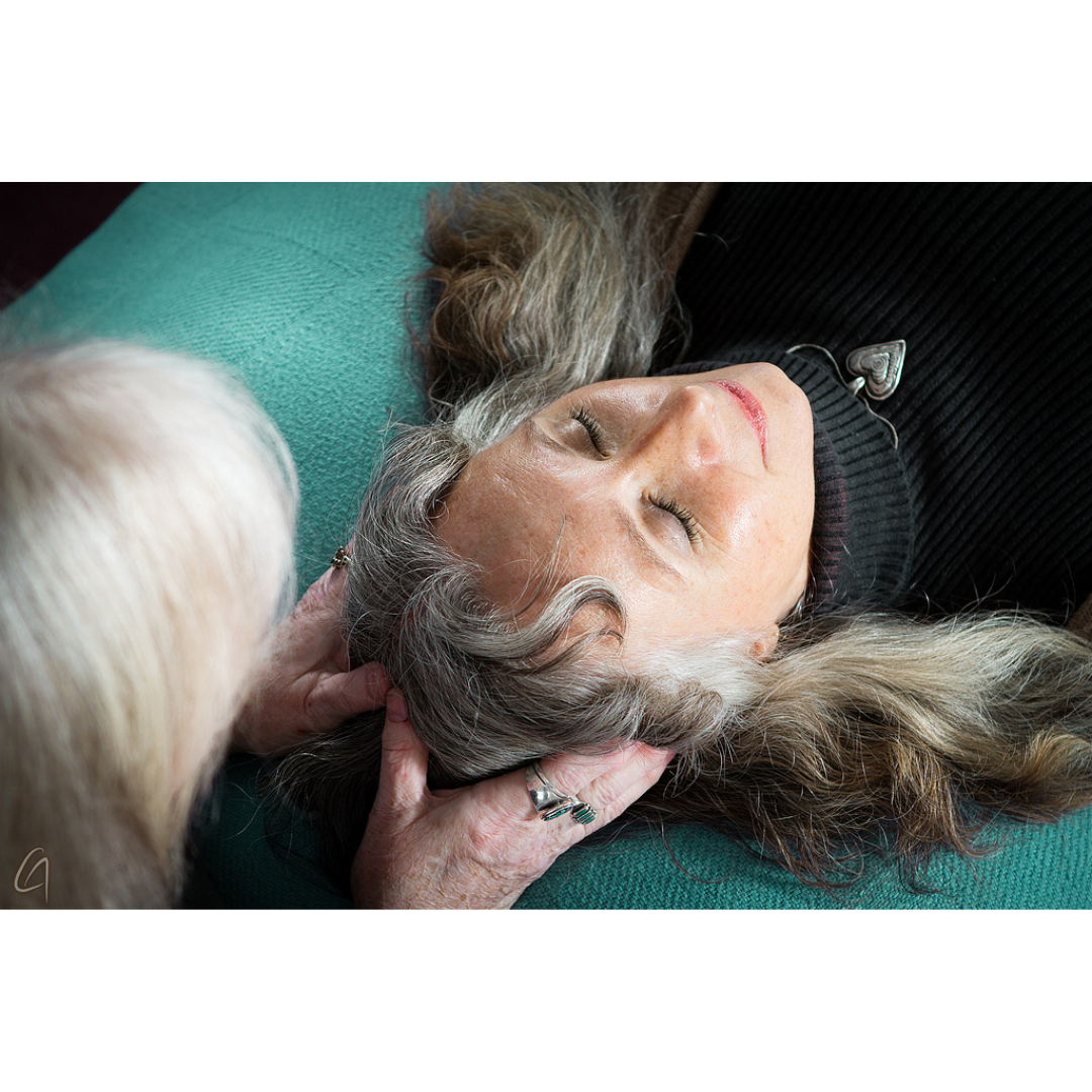 Client receiving a Healing Touch session — relaxed, fully clothed, hands lightly placed to balance energy field for stress relief and healing.