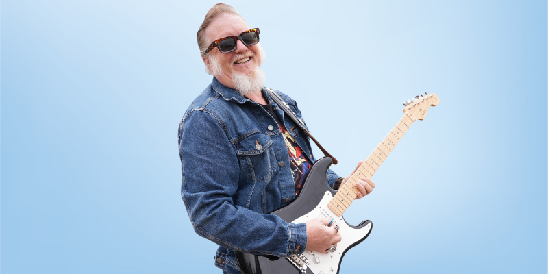 Chris Gordon, strategic manager and leadership team member at the Healing Touch Program, holding a guitar and smiling.