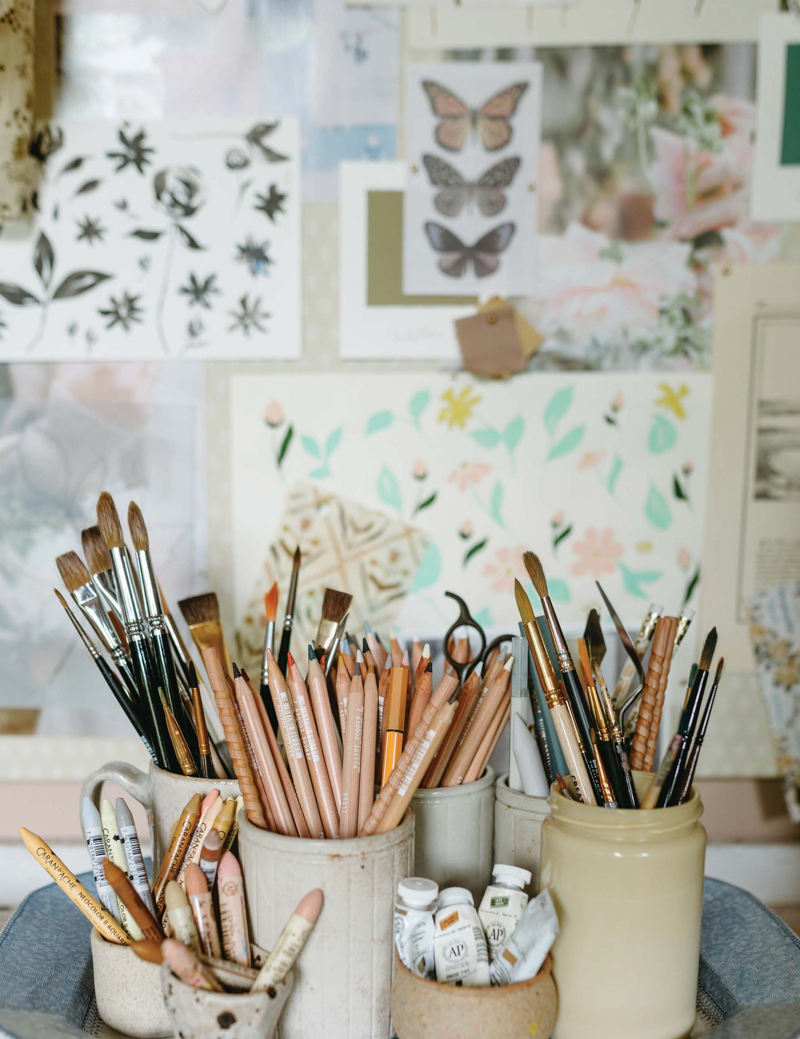 Jars of paintbrushes and pencils on a sunlit studio table