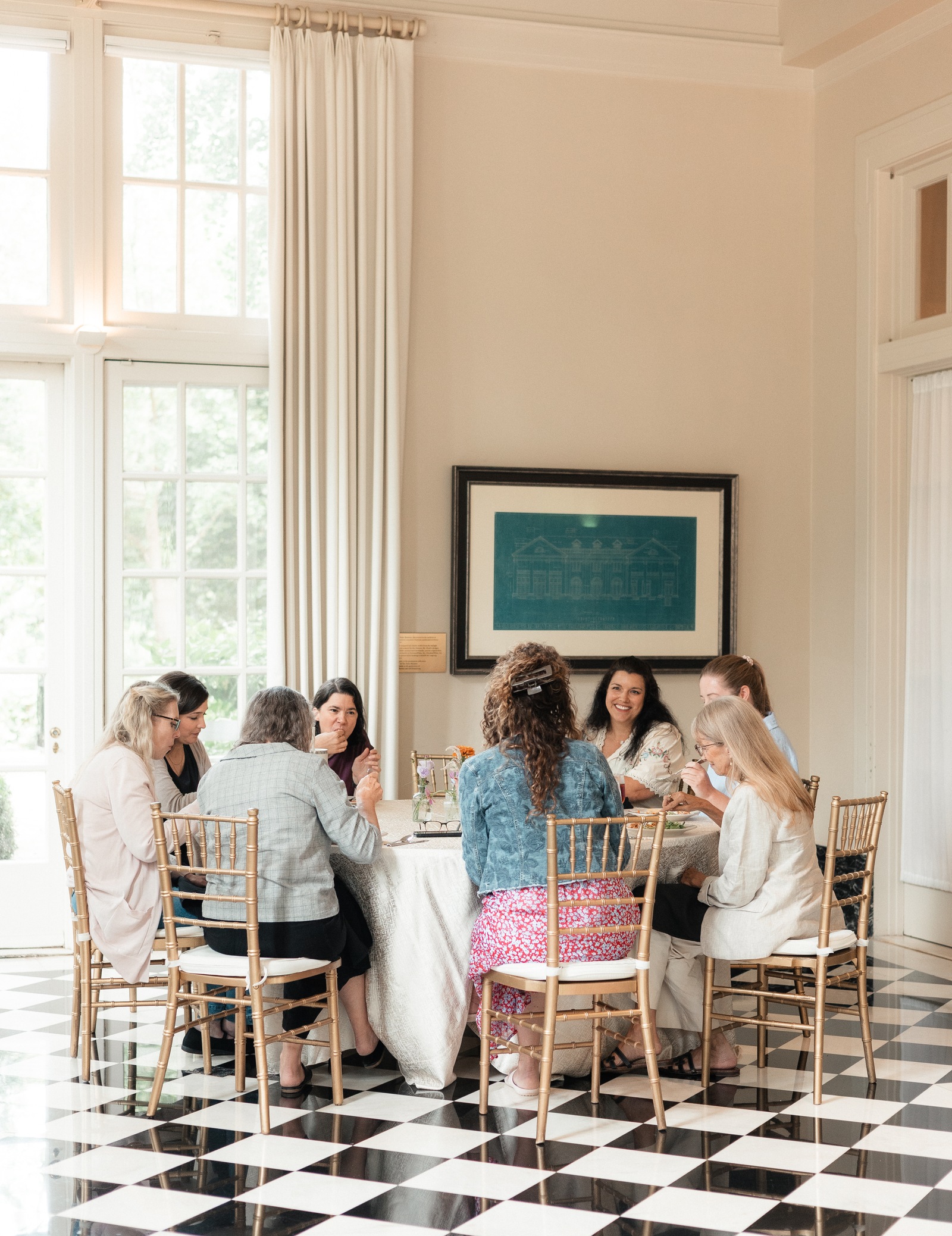 Women gathered around a long table at a Mark Makers Mastermind retreat, deep in conversation