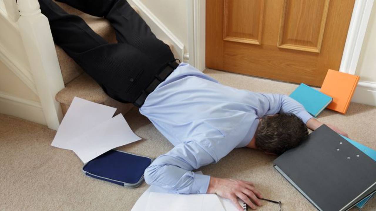 Man laying at the bottom of stairs with papers strewn around him