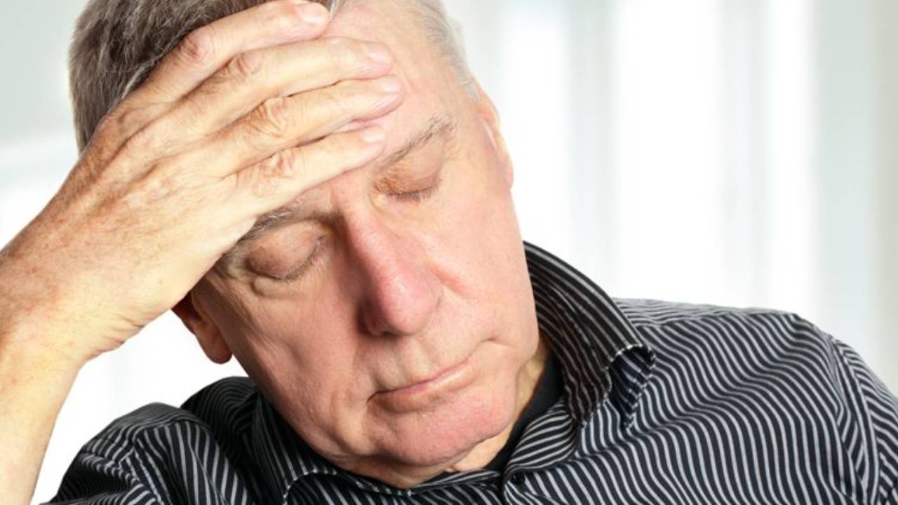 Sad old man with hand on his forehead