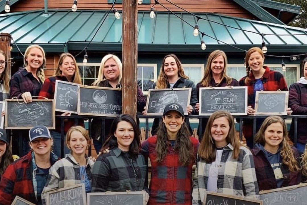 A group of M5 Entrepreneurs holding chalkboards with their business names at an in-person workshop