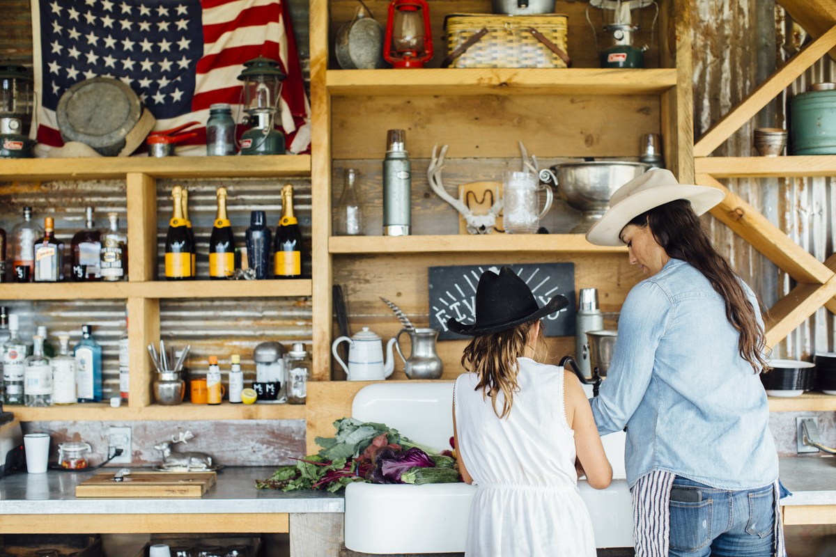 Two cowboy hats at the sink in the camp kitchen at Five Marys Ranch, washing vegetables