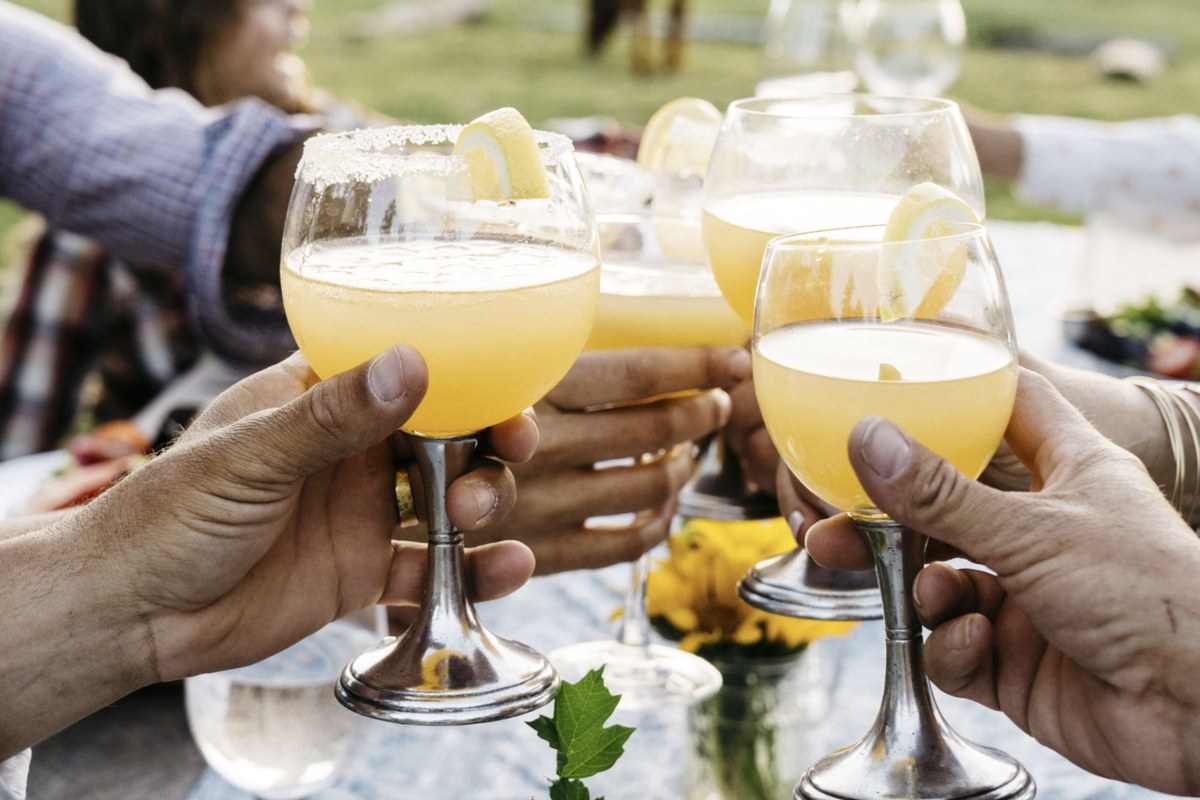 Hands raising glasses in a toast at an outdoor table on the ranch