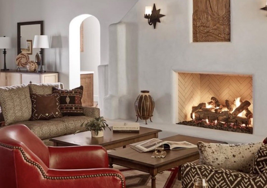 A lounge with a lit fireplace, leather chairs and southwestern textiles at Rancho de los Caballeros
