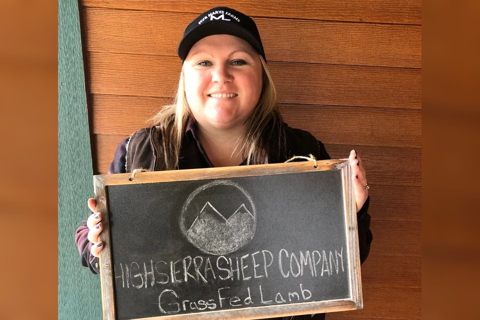 Niki Hammerich holding a High Sierra Sheep Company chalkboard sign