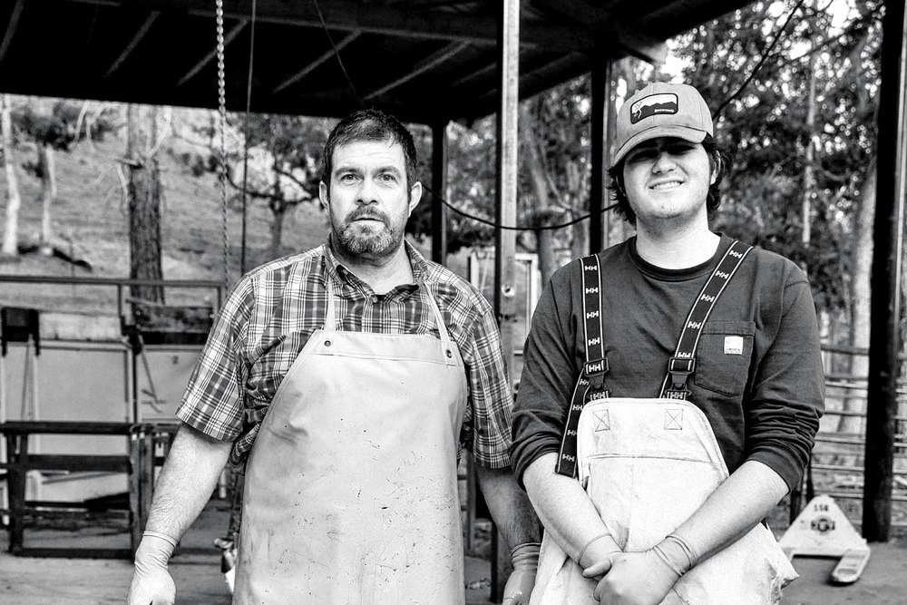 Two crew members in aprons by the mobile harvest unit