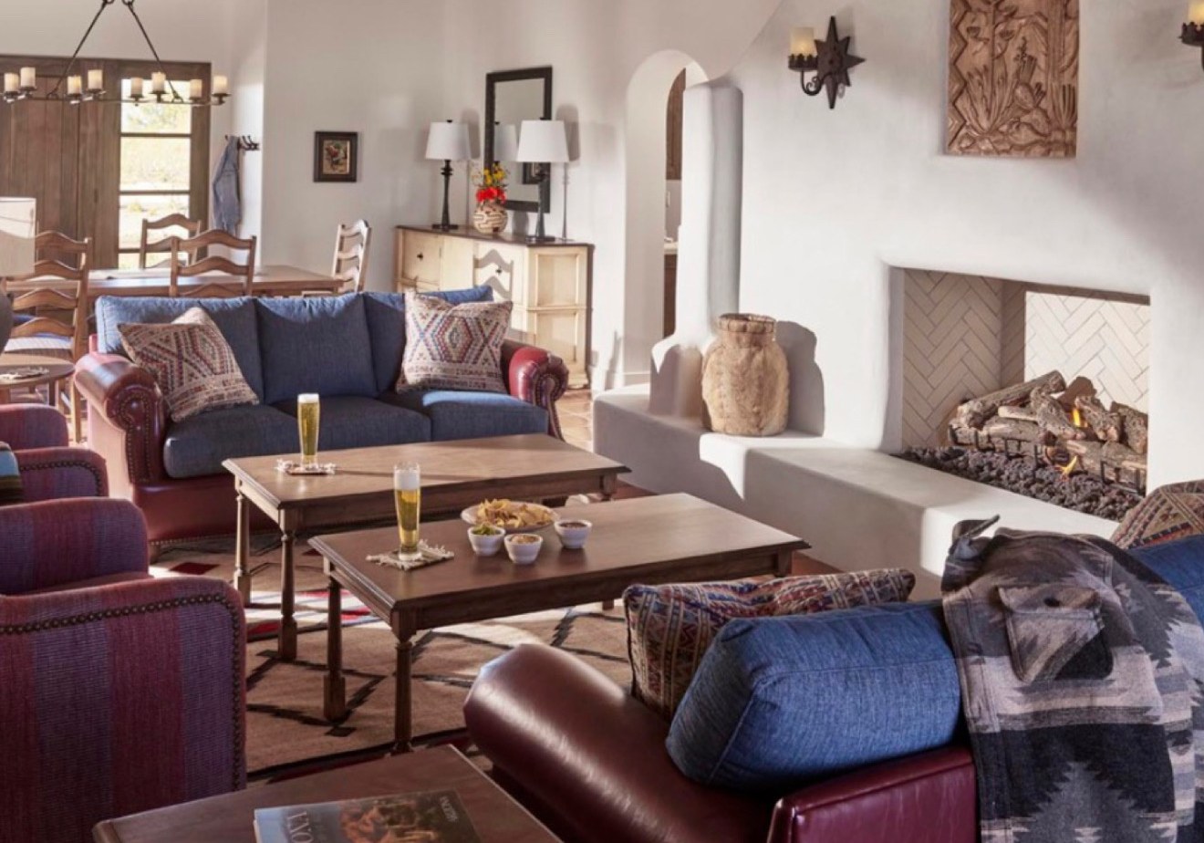 A sitting room with a fireplace and long wooden tables at Rancho de los Caballeros