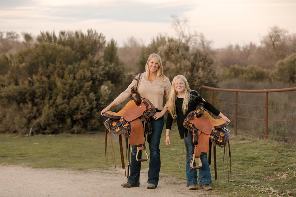 Amber Wighton and her daughter Abby holding kid saddles