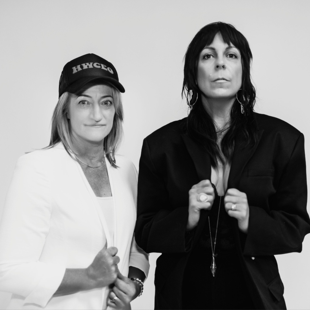 Black and white portrait of Marsha in a white blazer and ball cap standing beside a business partner in a black blazer