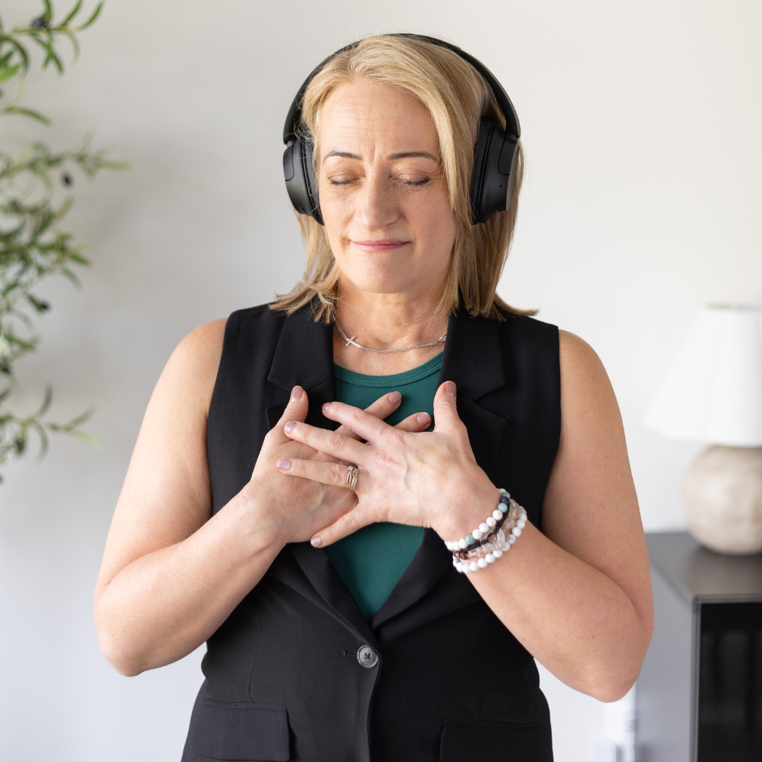 Marsha Vanwynsberghe wearing headphones with her eyes closed and hands resting on her heart