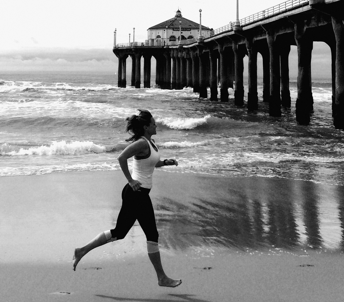 Alicia sprinting barefoot on the beach by the Manhattan Beach pier
