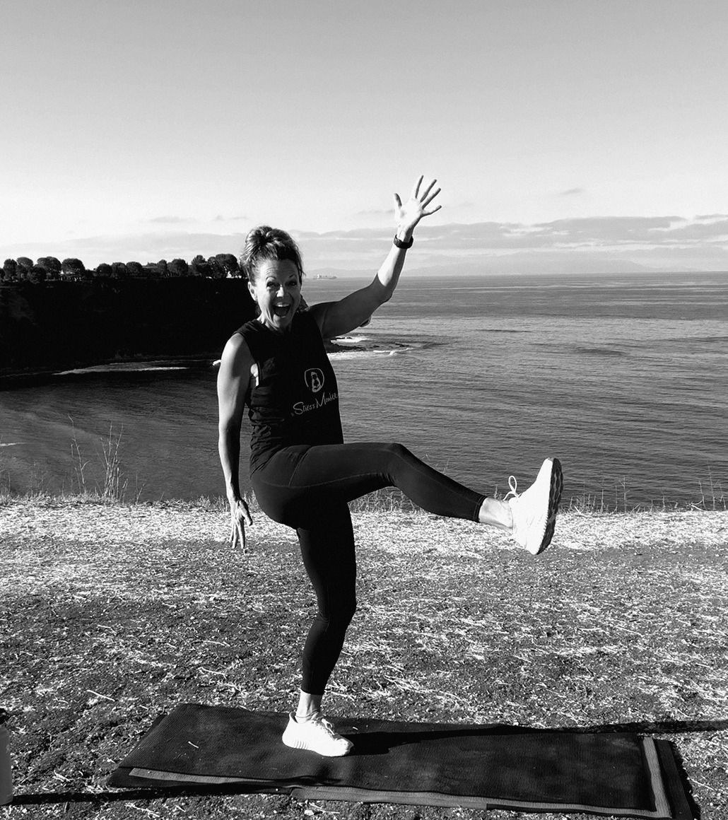 Alicia doing a playful high kick on the cliffs
