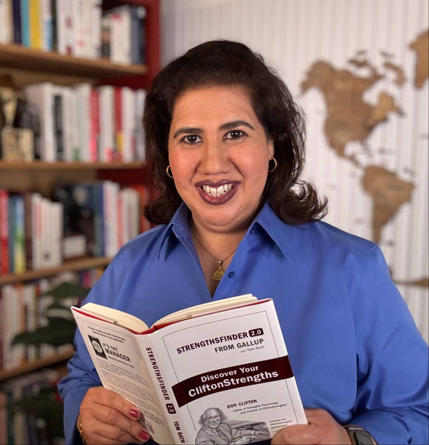 Elvira Marie Chang in her office, holding a copy of StrengthsFinder 2.0, Discover Your CliftonStrengths