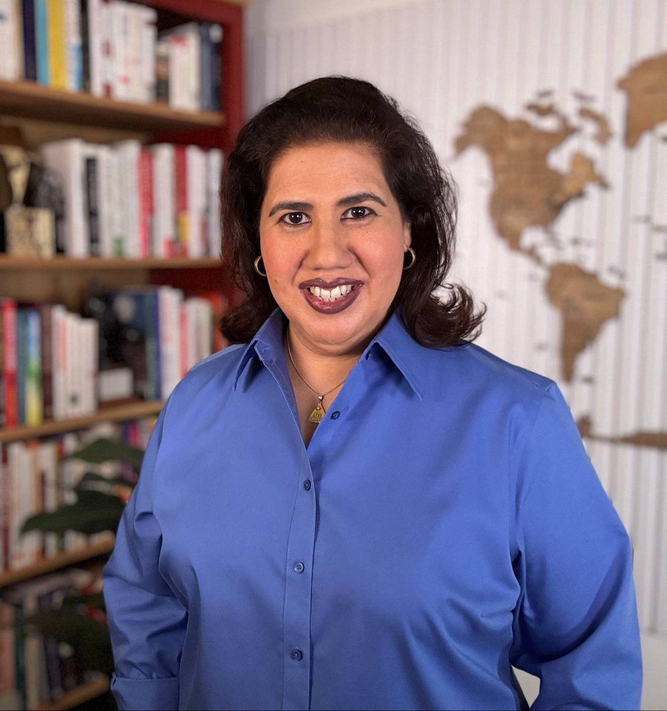 Elvira Marie Chang, Gallup-Certified Strengths Coach, standing in front of a bookshelf and a world map