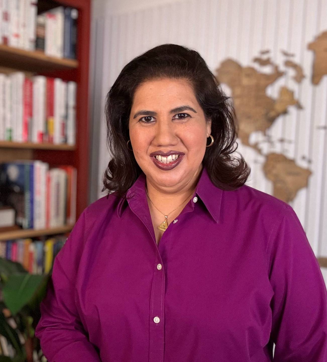 Elvira Marie Chang, Gallup-Certified Strengths Coach, standing in front of a bookshelf and a world map