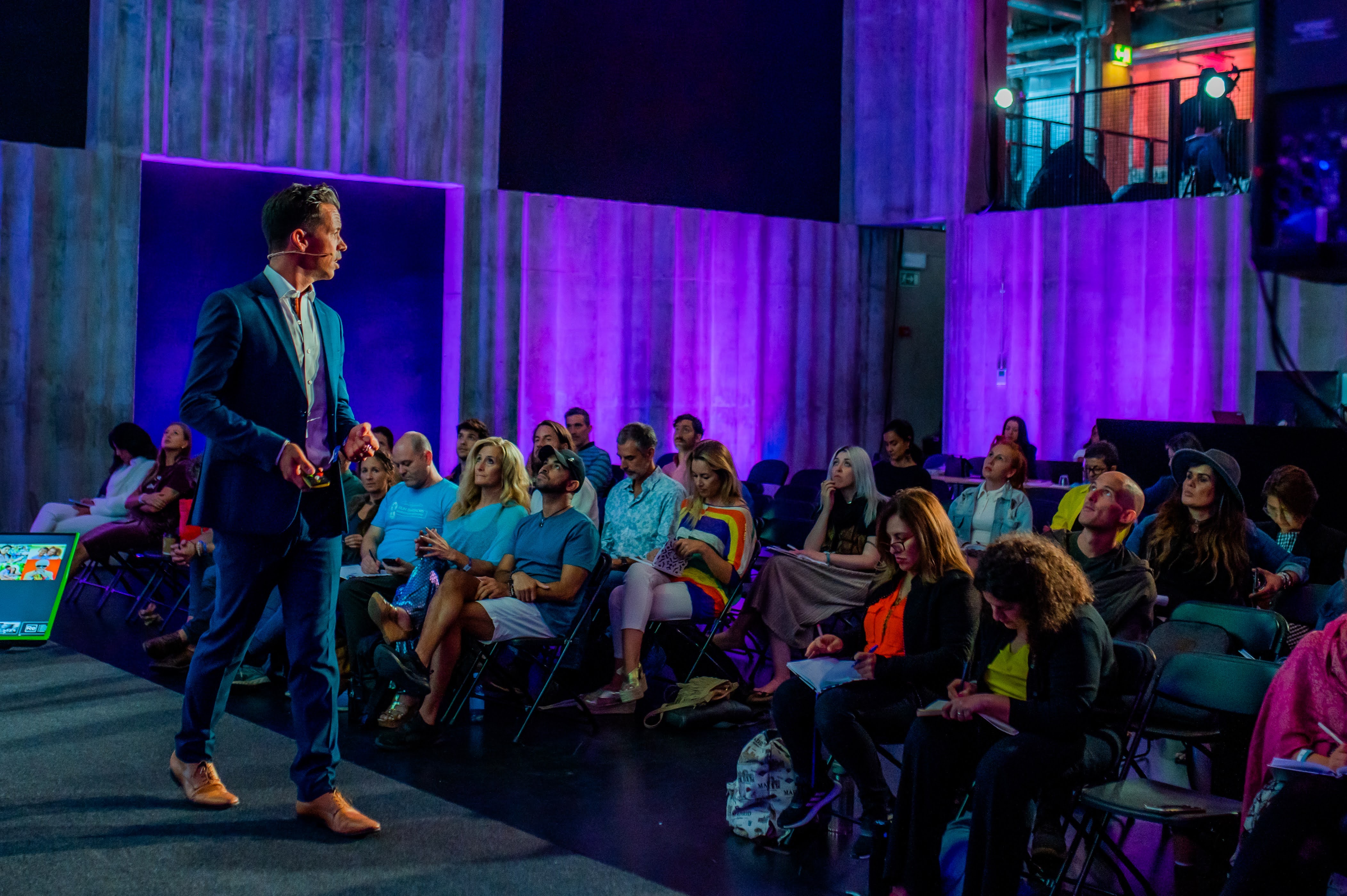Francis Piché speaking with an audience under purple stage lighting