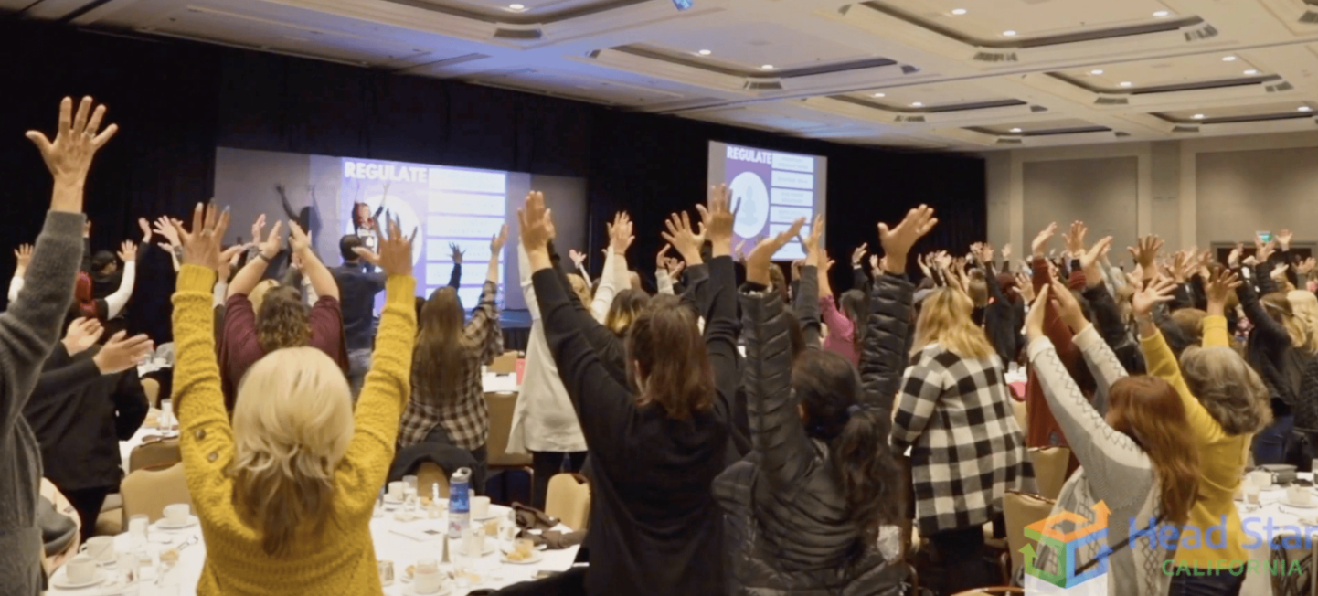 Head Start California keynote audience with hands raised