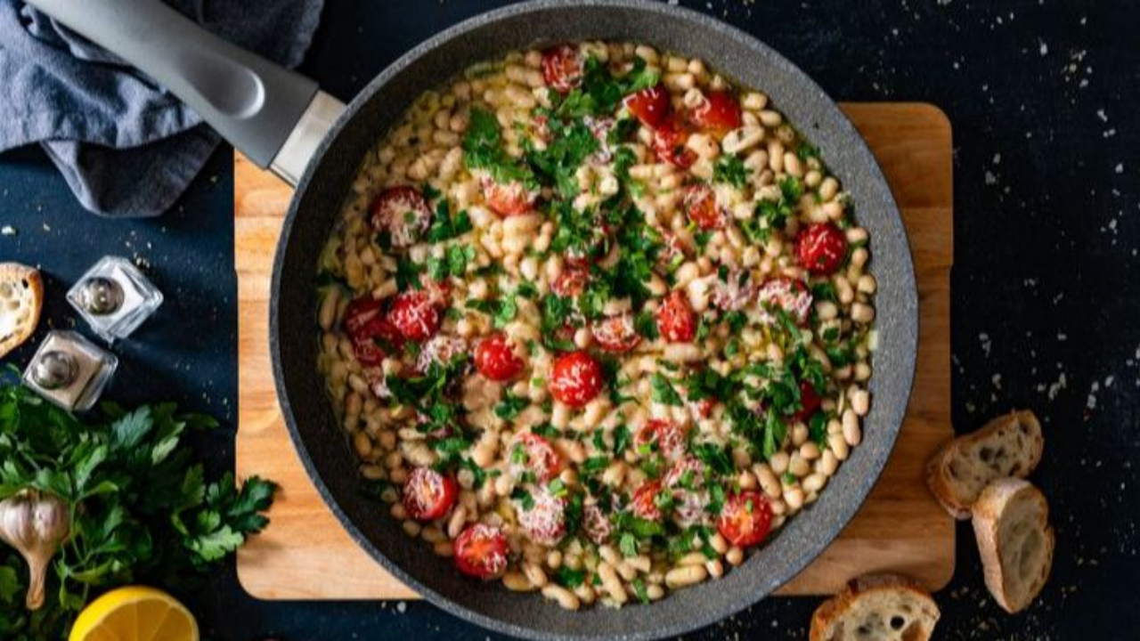 Italian white beans cooked with garlic, tomatoes, parmesan cheese, and fresh parsley in a rustic bowl