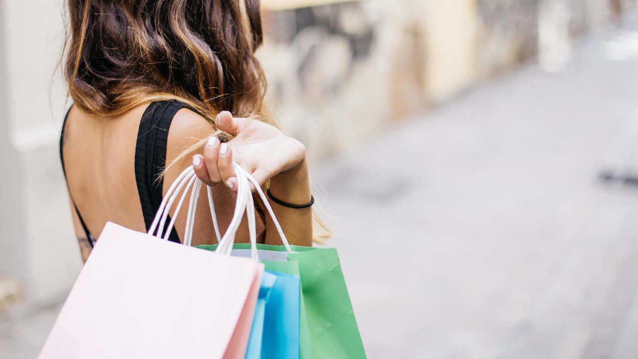Back of a woman carrying shopping bags representing emotional spending and money habits