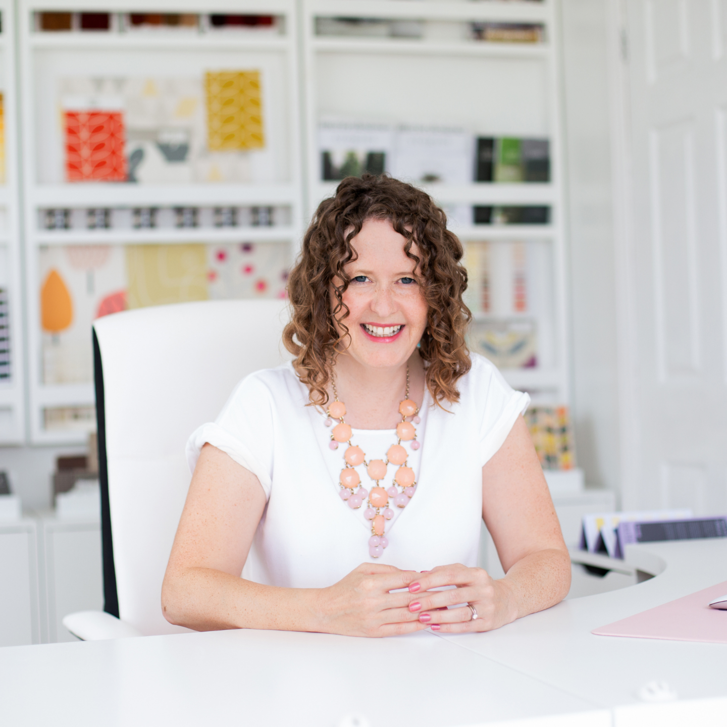 Photo of Kate Hatherell founder of The Interior Designers Hub sat at her desk with an interior styled background