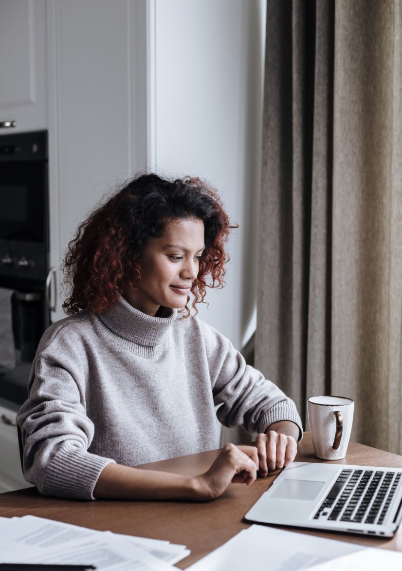 Woman working from home at a laptop with a cup of coffee