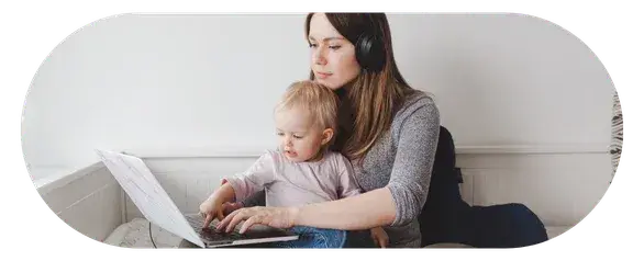 Parent holding a child while looking at a laptop