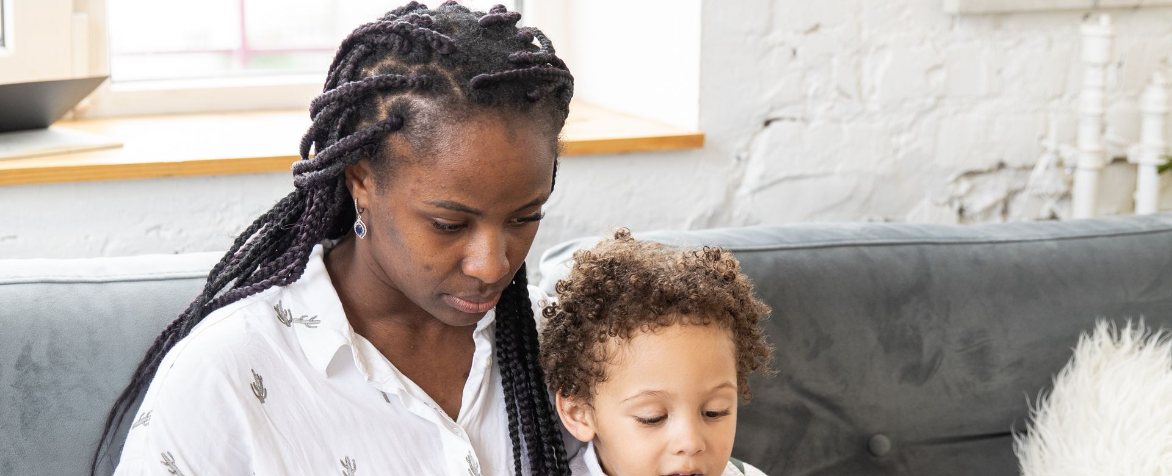 Mother with her young child on the couch, looking at a laptop