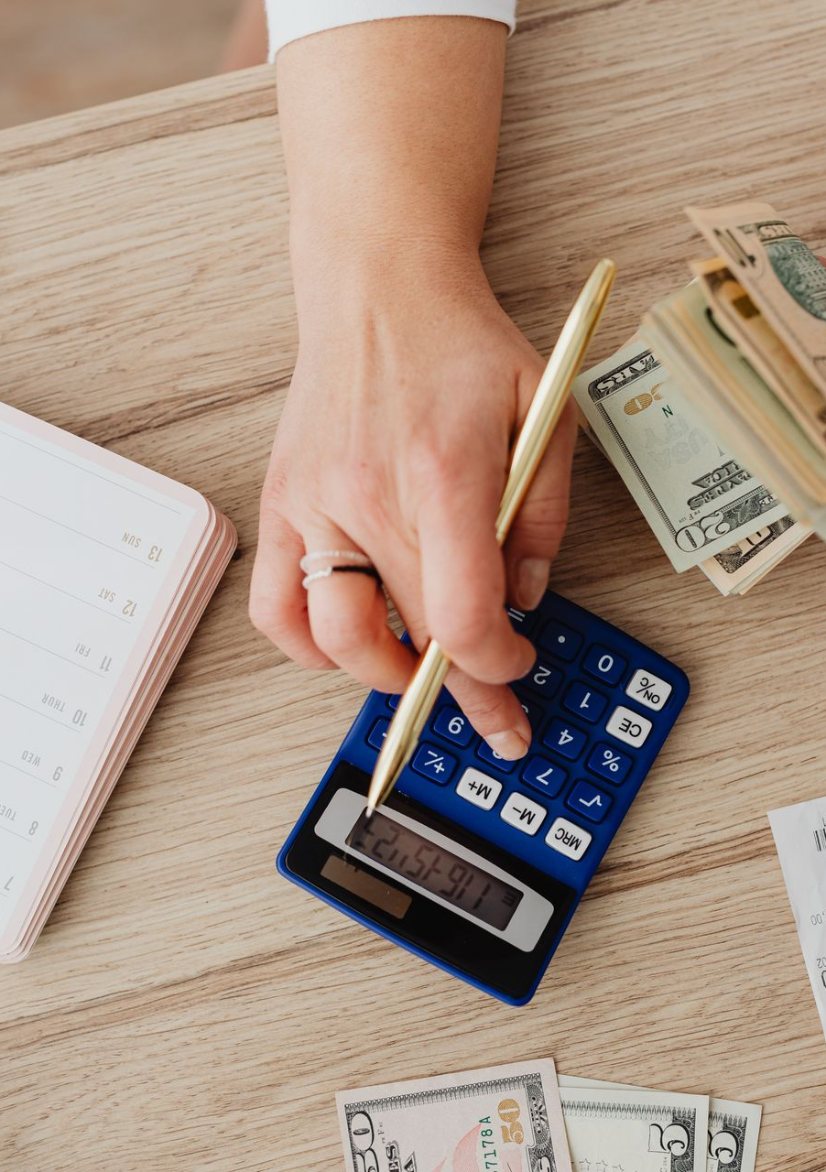 Person counting cash and using a calculator to work out a budget