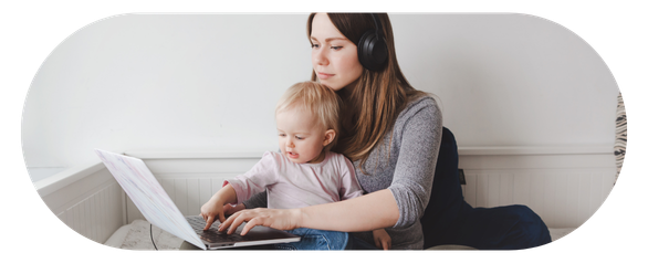 Parent holding a child while looking at a laptop
