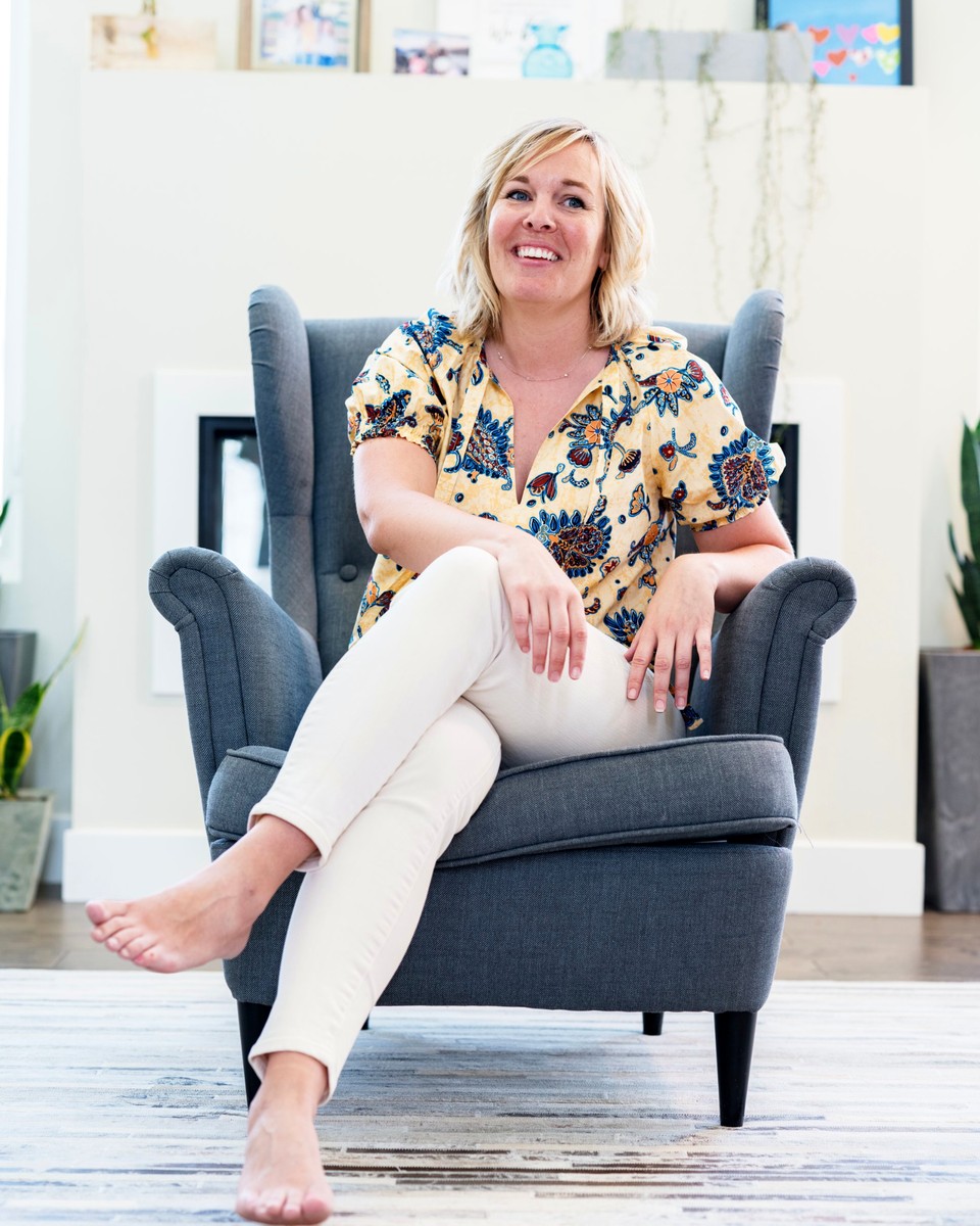 Sarah smiling in a gray wingback chair at home