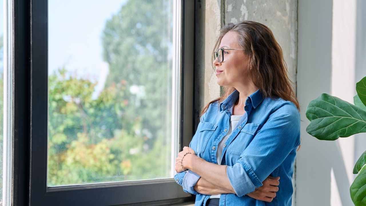 Woman reflecting by a window, illustrating recovery for adult children of narcissistic parents.