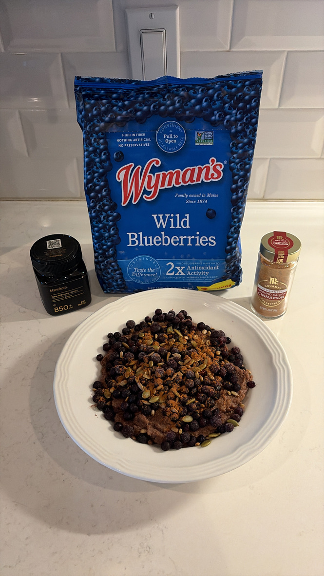 Chocolate cream of rice bowl topped with wild blueberries, pumpkin seeds, cinnamon and honey