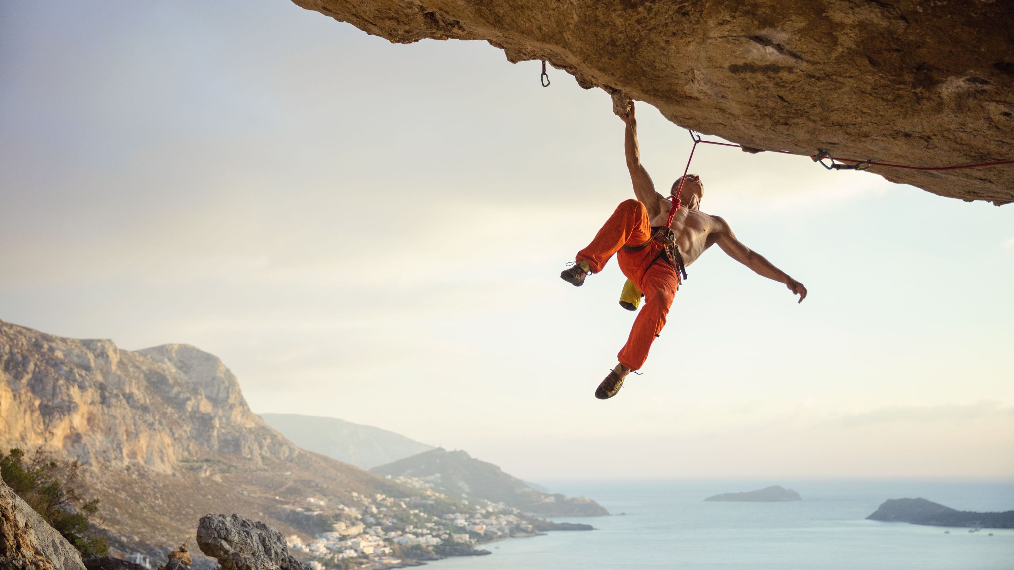 Young man climbing challenging route in cave against beautiful landscape